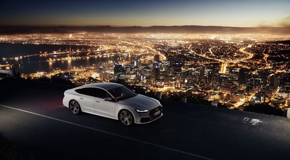 Обои на рабочий стол Белый автомобиль Audi A7 мчится на фоне огней ночного города
