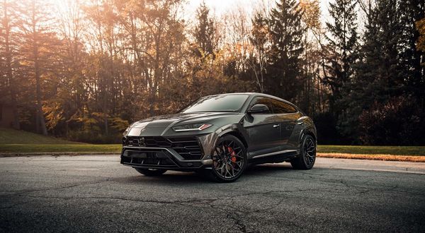 Обои на рабочий стол Черный суперкар Lamborghini Urus стоит возле осеннего парка
