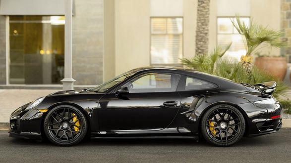 Обои на рабочий стол Черный суперкар Porsche 911 Turbo стоит возле здания