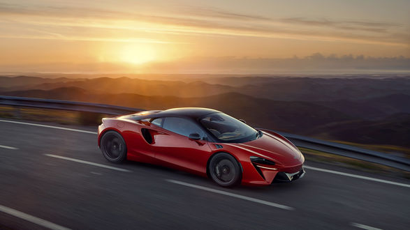 Обои на рабочий стол Красный спорткар McLaren Artura мчится на фоне заката солнца
