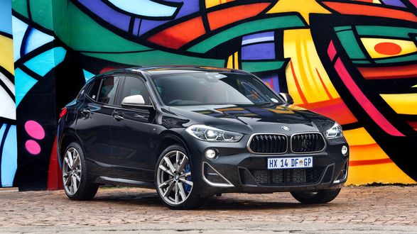 Обои на рабочий стол Черный автомобиль BMW X2 стоит на фоне граффити
