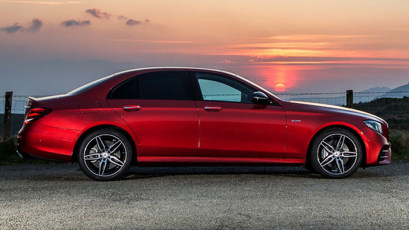 Обои на рабочий стол Красный автомобиль Mercedes-AMG E 43 стоит на фоне красного закатного неба