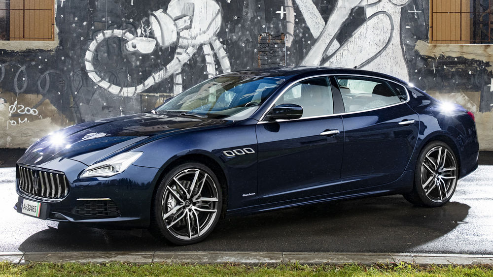Обои для рабочего стола Синий седан Maserati GranLusso стоит у стены с граффити