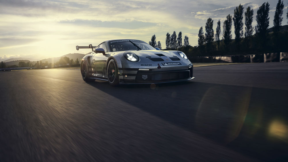 Обои для рабочего стола Серебристый спорткар Porsche 911 GT3 мчится по дороге в лучах солнечного света