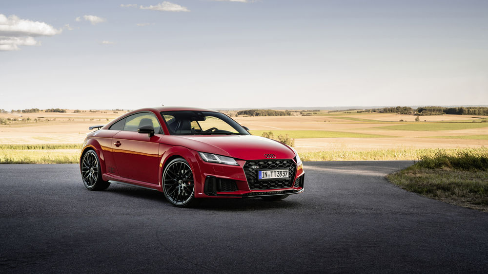 Обои для рабочего стола Красный автомобиль Audi TT стоит на дороге в поле