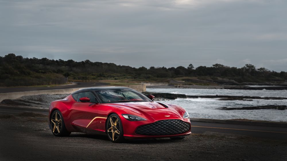 Обои для рабочего стола Красный спорткар Aston Martin DBS GT Zagato стоит у дороги возле реки