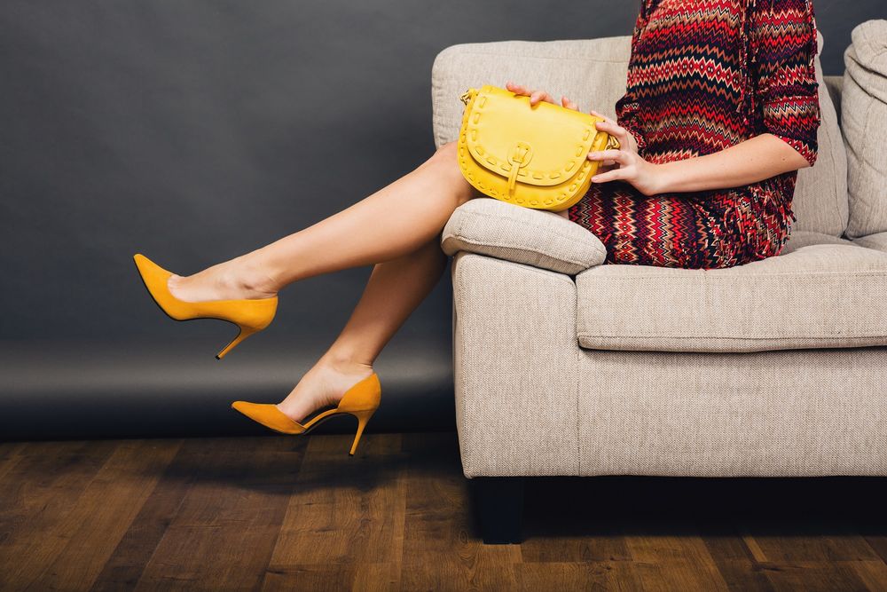 Обои для рабочего стола Девушка с сумочкой сидит на диване, опустив ножки в туфельках, фотограф Marymarkevich