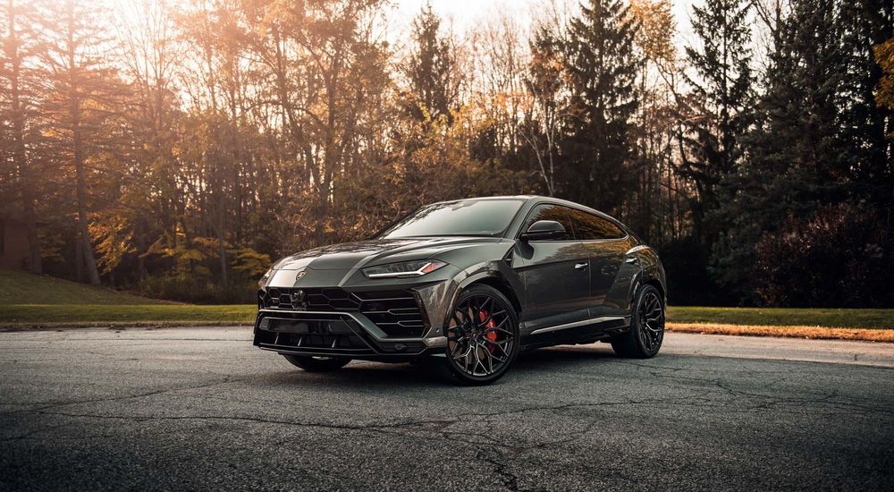 Обои для рабочего стола Черный суперкар Lamborghini Urus стоит возле осеннего парка