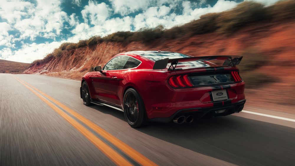 Обои для рабочего стола Красный автомобиль Ford Mustang Shelby GT500 мчится по дороге