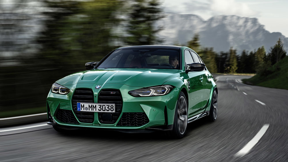 Обои для рабочего стола Зеленый автомобиль BMW M3 Competition мчится по горной дороге