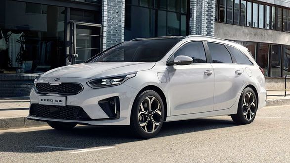 Обои на рабочий стол Белый автомобиль на фоне городского здания СереKia ceed SW