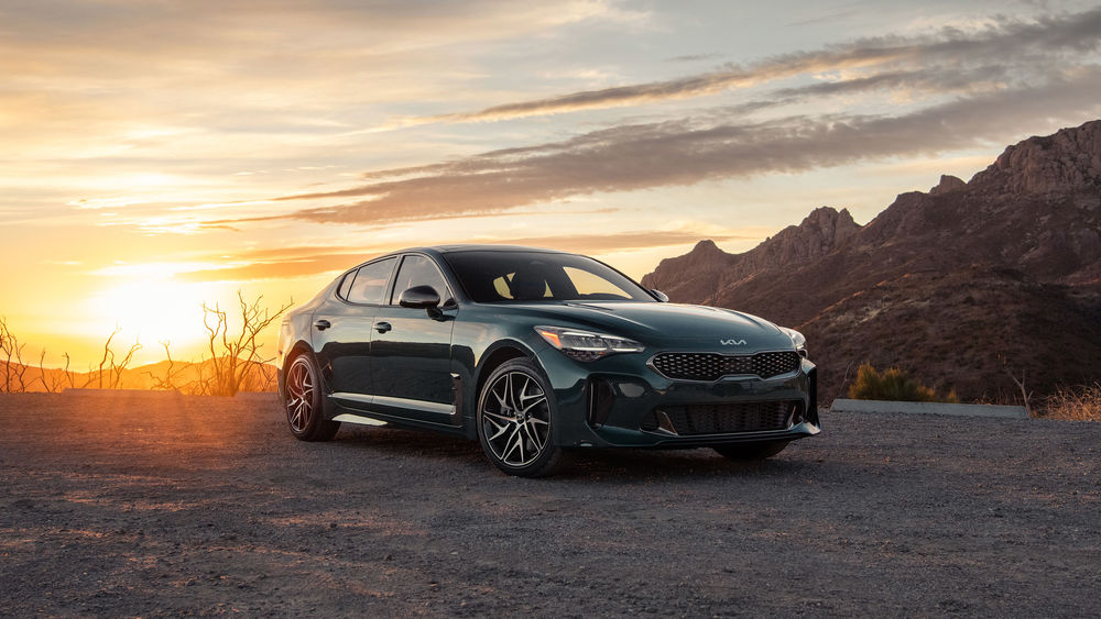 Обои для рабочего стола Автомобиль зеленого цвета Kia Stringer стоит на фоне заката солнца