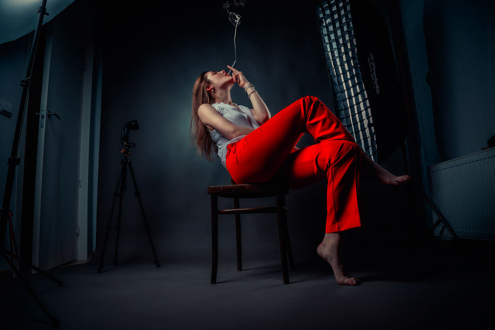 Обои для рабочего стола Девушка в красных брюках с сигаретой в руке сидит на стуле, фотограф Сизиков Николай