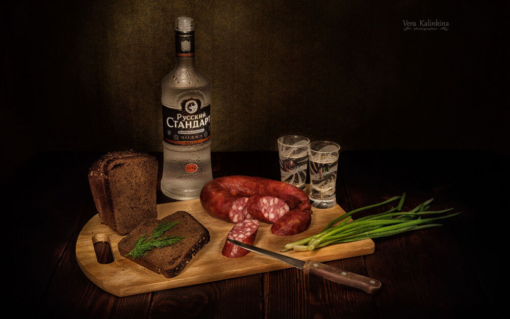 Обои для рабочего стола Доска с колбаской, луком и хлебом и бутылкой водки Русский стандарт