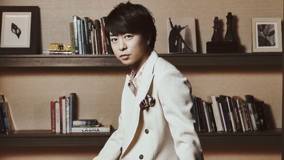 Обои на рабочий стол Певец, актер и телеведущий Сакурай Шо / Sakurai Sho из группы Араши / Arashi стоит в костюме на фоне полок, на которых есть книги, фото, картины и шахматы