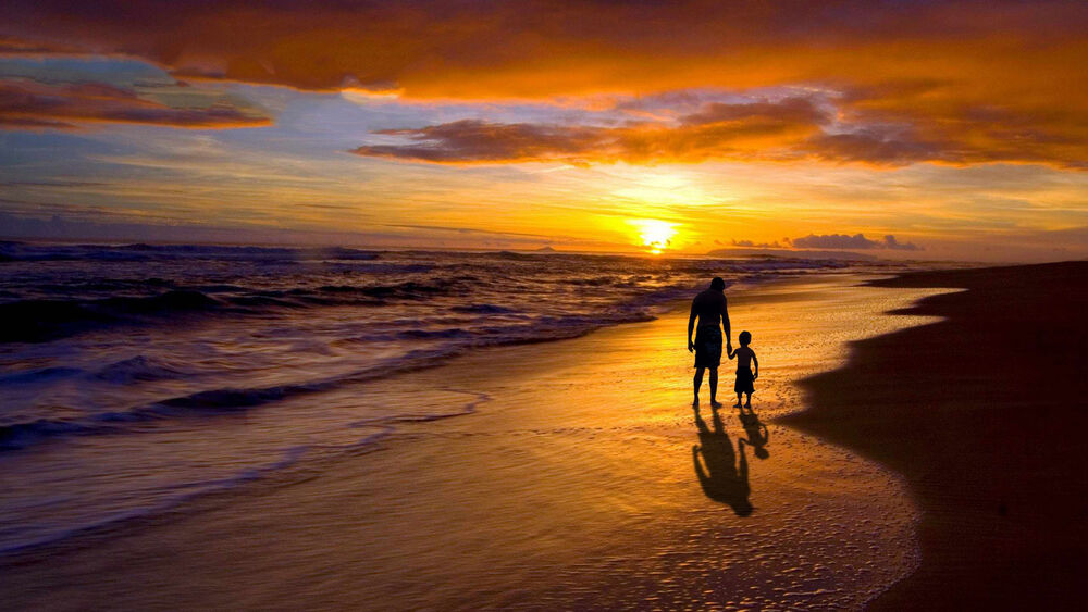Обои для рабочего стола Отец с сыном гуляют вдоль морского берега в лучах закатного неба