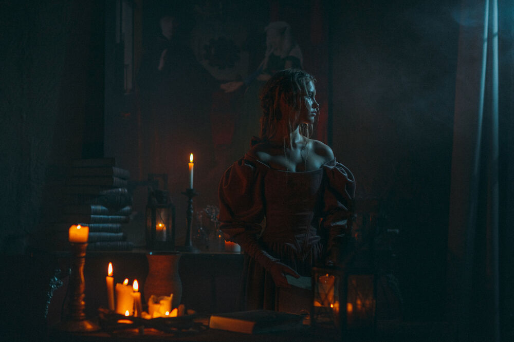 Обои для рабочего стола Девушка стоит в комнате с горящими свечами. Фотограф Мытник Валерия