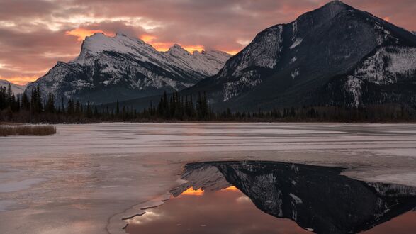 Обои на рабочий стол Покрытое льдом горное озеро на фоне занесенных снегом вершин в сумерках
