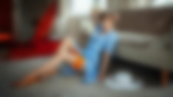 Обои для рабочего стола Девушка-модель Каролина Шимчак в голубом платье и оранжевых чулках позирует сидя на полу возле дивана, фотограф Oliver Gibbs