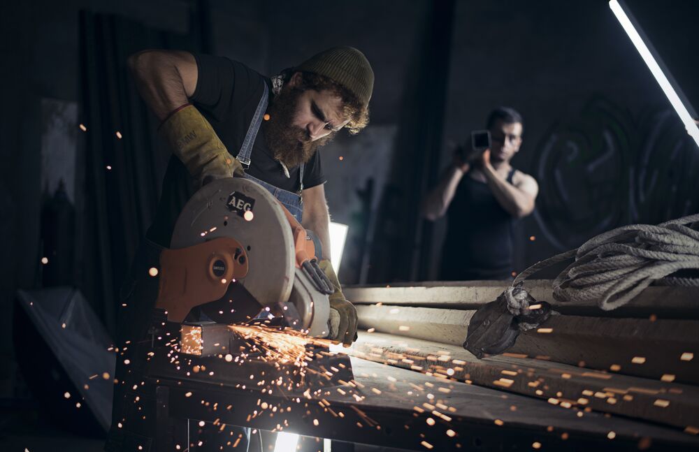 Обои для рабочего стола Мужчины работают с металлом в мастерской искры из под циркулярной пилы