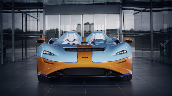 Обои на рабочий стол Голубой с коричневой полосой MCLAREN Elva у здания