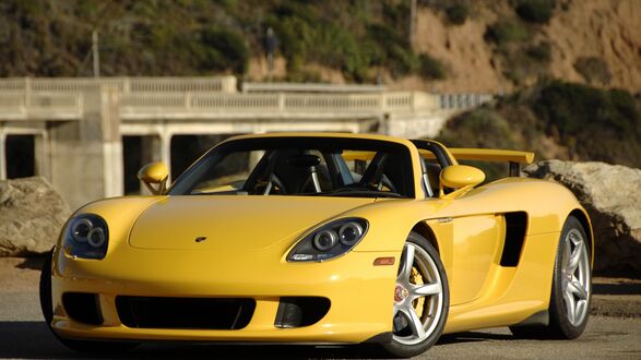 Обои на рабочий стол Желтый Porsche Carrera GT у моста