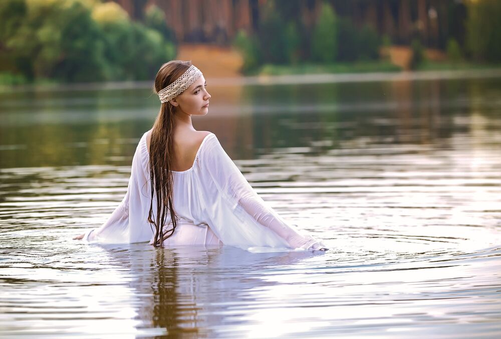 Обои для рабочего стола Модель Мария Давыдова с повязкой на голове и в белом балахоне стоит в водоеме на размытом фоне природы, фотограф Виталий Вахрушев