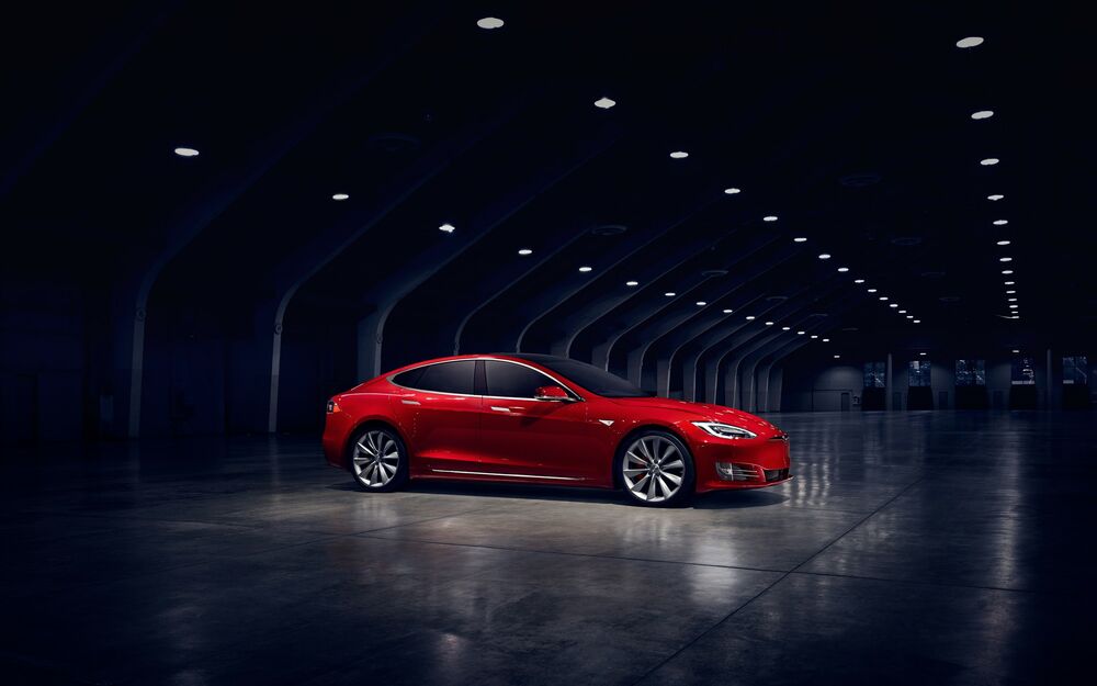 Обои для рабочего стола Тesla model s стоит в полутемном ангаре