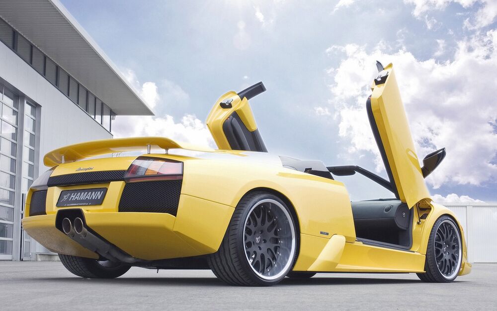 Обои для рабочего стола Суперкар Lamborghini Murcialago стоит полубоком возле здания