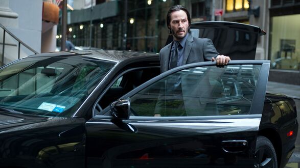 Обои на рабочий стол Keanu Reeves / Киану Ривз в роли Джона Уика из фильма John Wick / Джон Уик, у черной машины в сером костюме