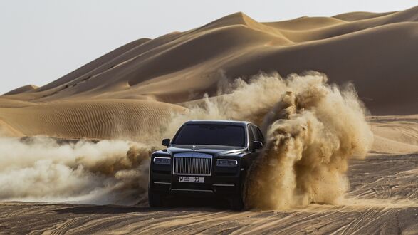 Обои на рабочий стол Черный Rolls Royce В пустыне в клубах песка на фоне бархан