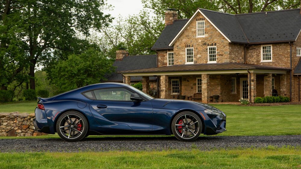 Обои для рабочего стола Синий автомобиль Toyota Supra стоит у каменного дома