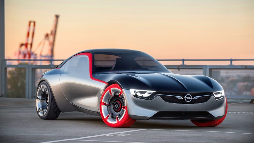 Обои для рабочего стола Концепт кар с красными колесами Opel GT стоит на стоянке на фоне закатного неба