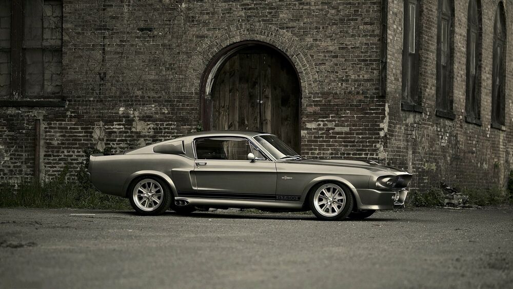 Обои для рабочего стола Ford Shelby Mustang 69 в обвесе Элеонор, стоит у старого кирпичного здания