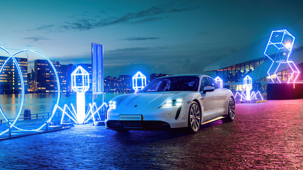 Обои для рабочего стола Porsche Taycan белого цвета стоит на набережной возле неоновых фигур