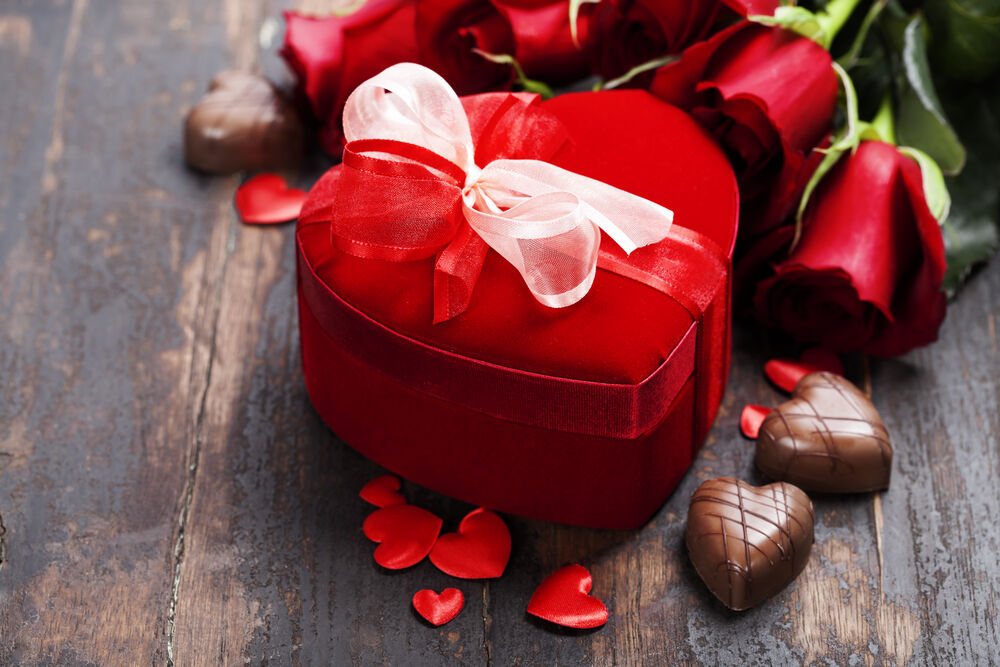 Обои для рабочего стола Подарок в форме сердца рядом с цветами, сердечками и конфетами в форме сердечек