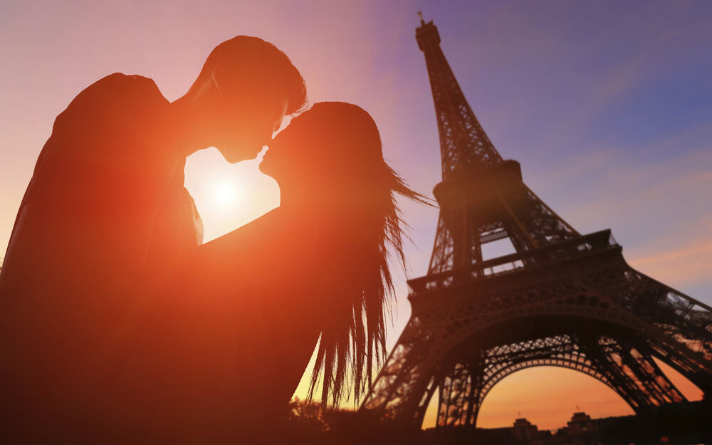 Обои для рабочего стола Влюбленные целуются на фоне Эйфелевой башни