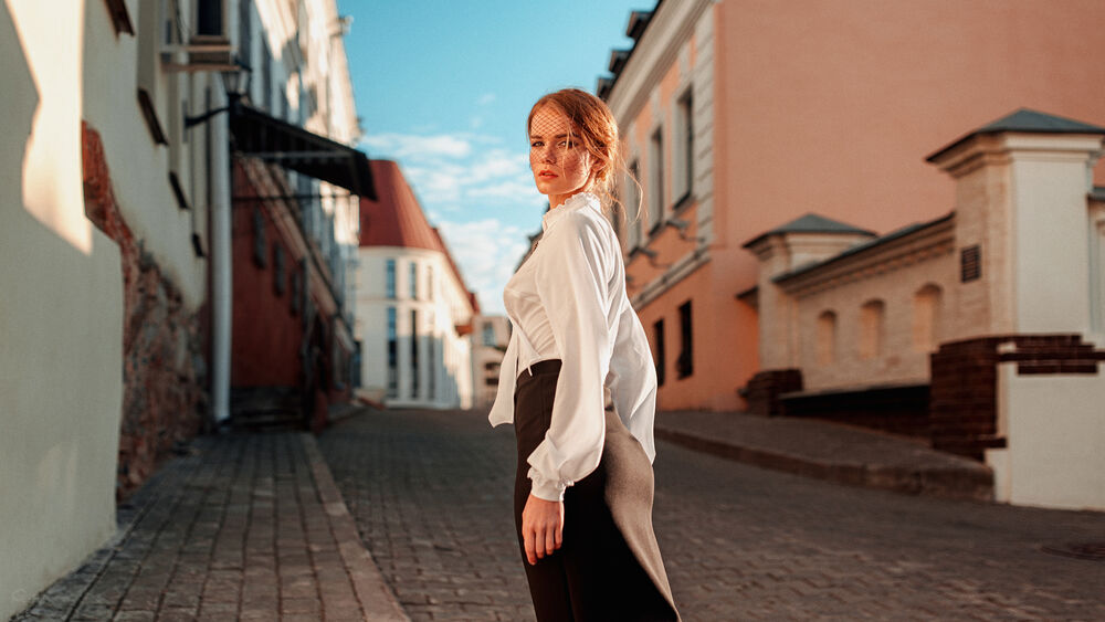 Обои для рабочего стола Модель Ирина Регент в белой блузке и в юбке стоит городской улице