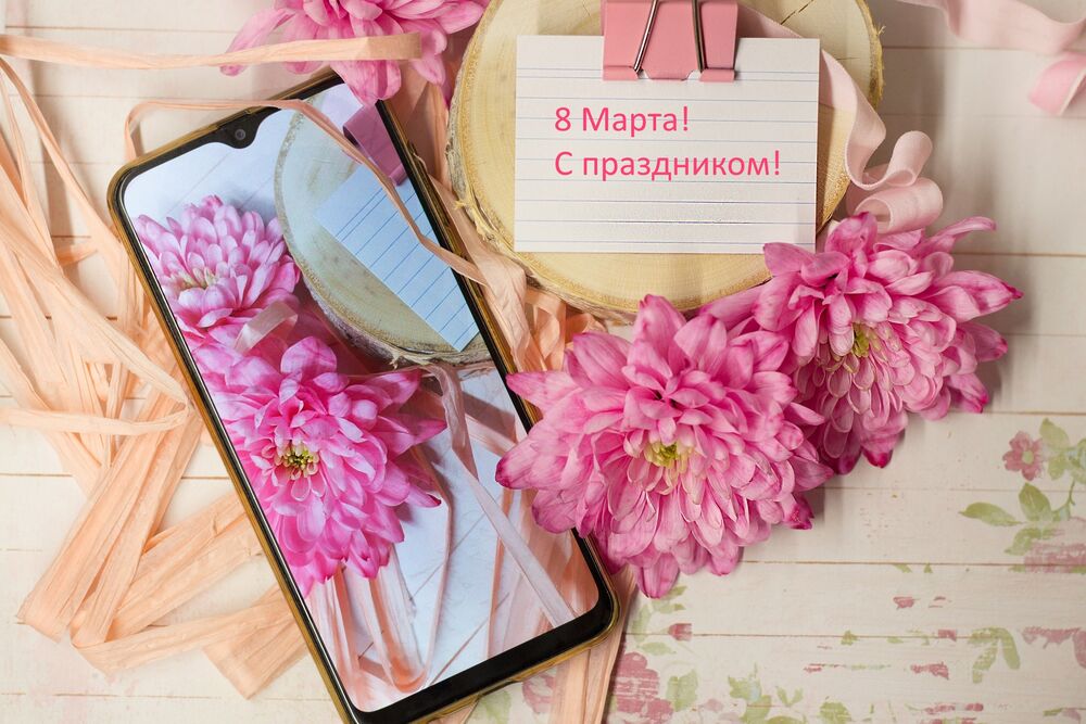 Обои для рабочего стола Записка с надписью 8 марта, с праздником! рядом с розовыми цветами и телефоном
