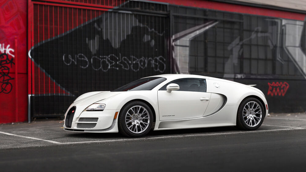 Обои для рабочего стола Белый Bugatti Veyron стоит на фоне черно-красной стены