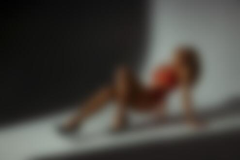 Обои для рабочего стола Модель Алла в красном нижнем белье стоит в приподнятой на руках и ногах позе на темном фоне помещения