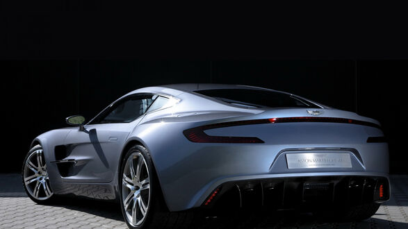 Обои на рабочий стол Серебристый Aston Martin сзади на брусчатке
