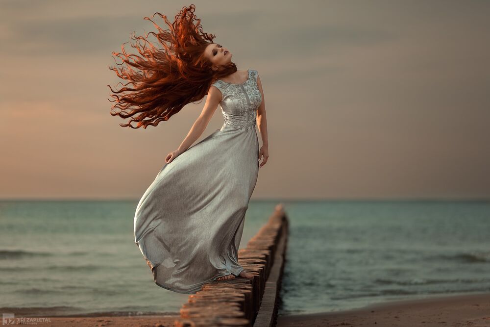 Обои для рабочего стола Модель Lena Zemanova / Лена Земанова c развевающимися волосами в длинном светлом платье стоит на фоне моря