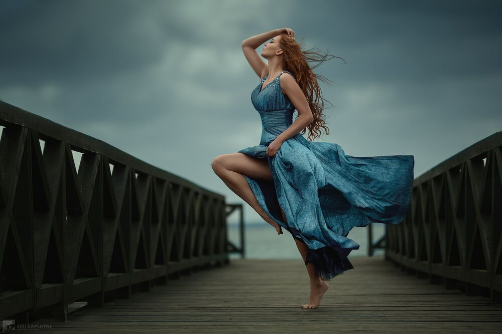 Обои для рабочего стола Модель Lena Zemanova / Лена Земанова в длинном голубом платье стоит на мосту, приподняв ножку