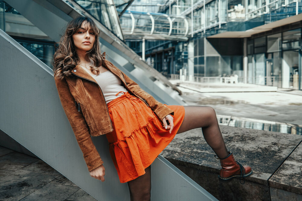 Обои для рабочего стола Модель Sarah S. в оранжевой юбке и курточке позирует у какой-то конструкции