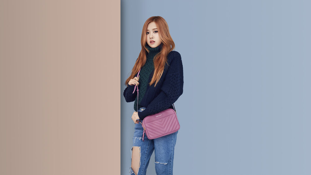Обои для рабочего стола Розэ / Rose из BLACKPINK в джинсах, кофте и с сумочкой на бежево-синем фоне