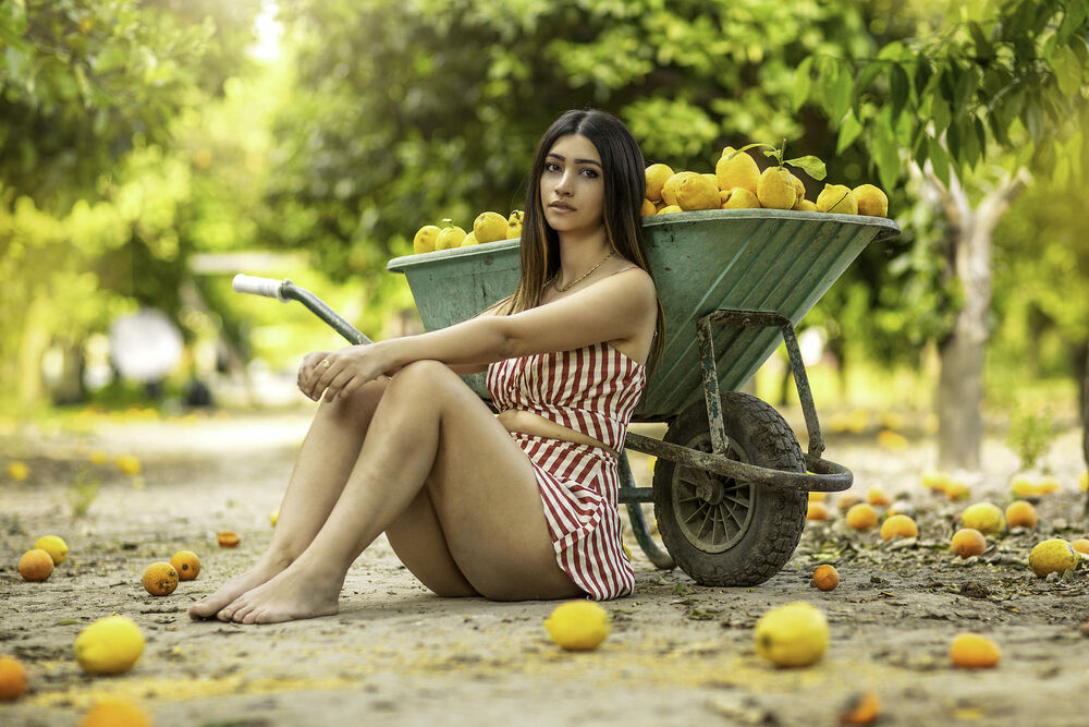 Обои для рабочего стола Девушка сидит на дороге у тачки с лимонами