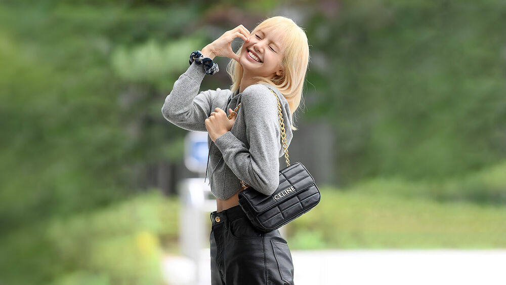 Обои для рабочего стола Лалиса / Lalisa из музыкальной группы Блэкпинк / Blackpink улыбается позируя на улице с сумочкой CELINE