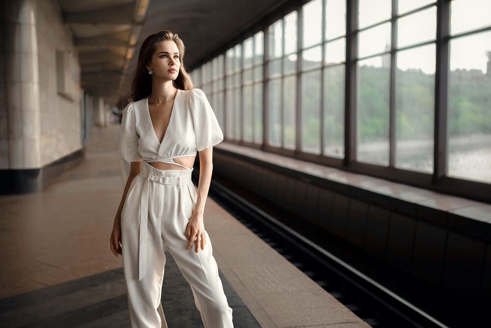 Обои для рабочего стола Модель Кристина в белом топе и в брюках стоит в вестибюле станции метро Воробьевы горы