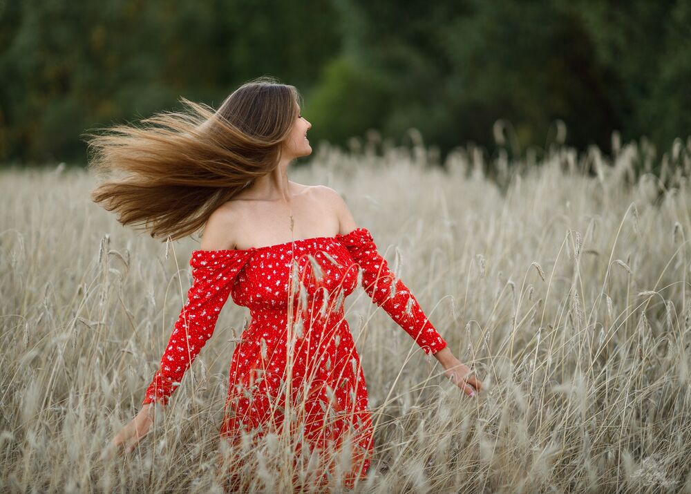 Обои для рабочего стола Модель Анастасия Романова в красном платье стоит в высокой траве на опушке леса